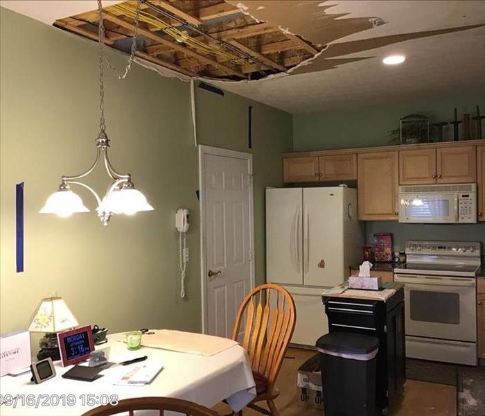 Water damaged kitchen with buckled hardwood floor, sagging ceiling, and wet drywall.